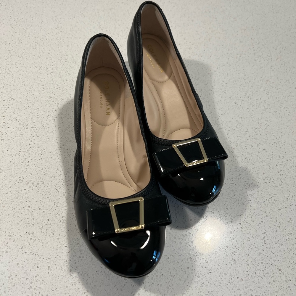 Cole Haan black wedge pump. Black leather with patent toe and bow.